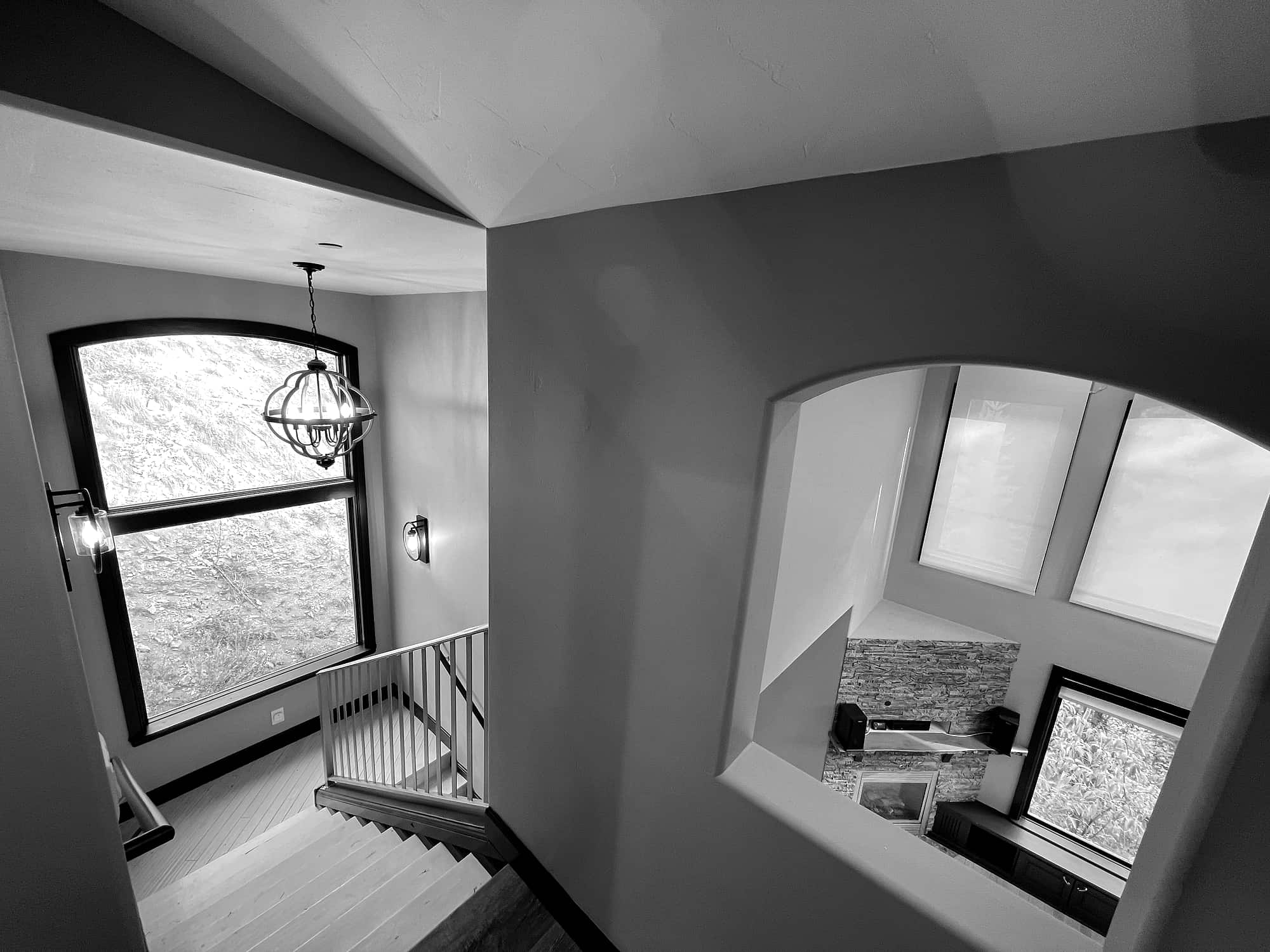 The stairwell, arched window above a cut-out view to the great room