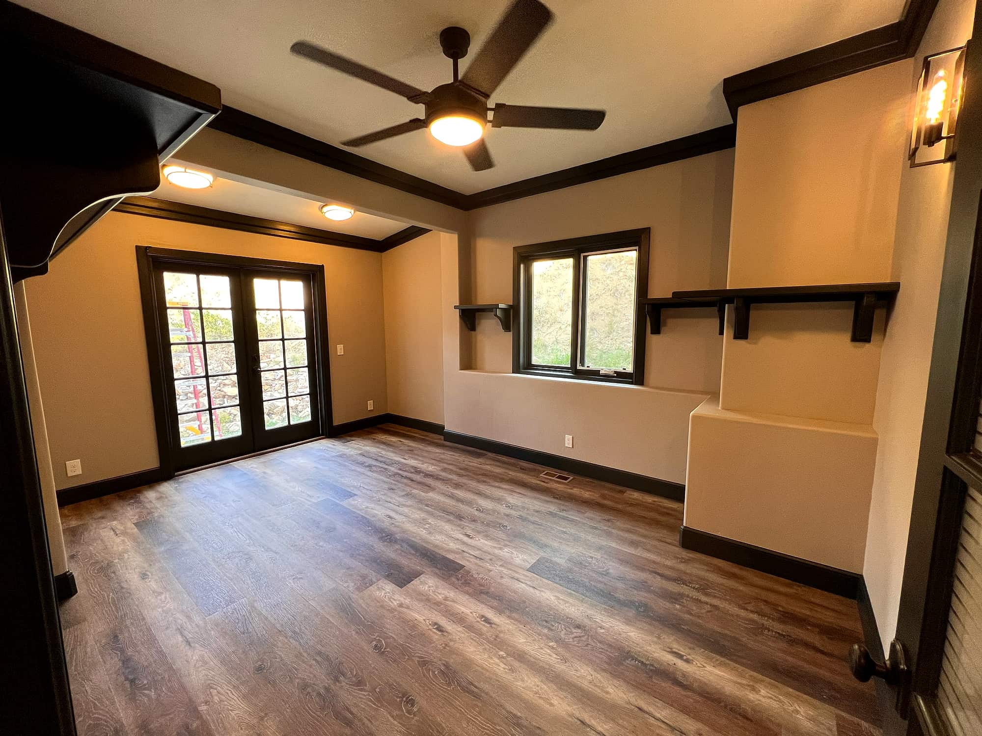 A bedroom with dark trim, built-in shelving and French doors