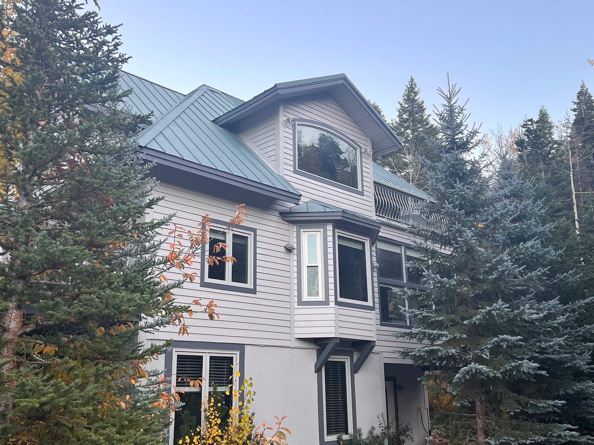 The residence seen from the front, its gable and balcony rising above the pines