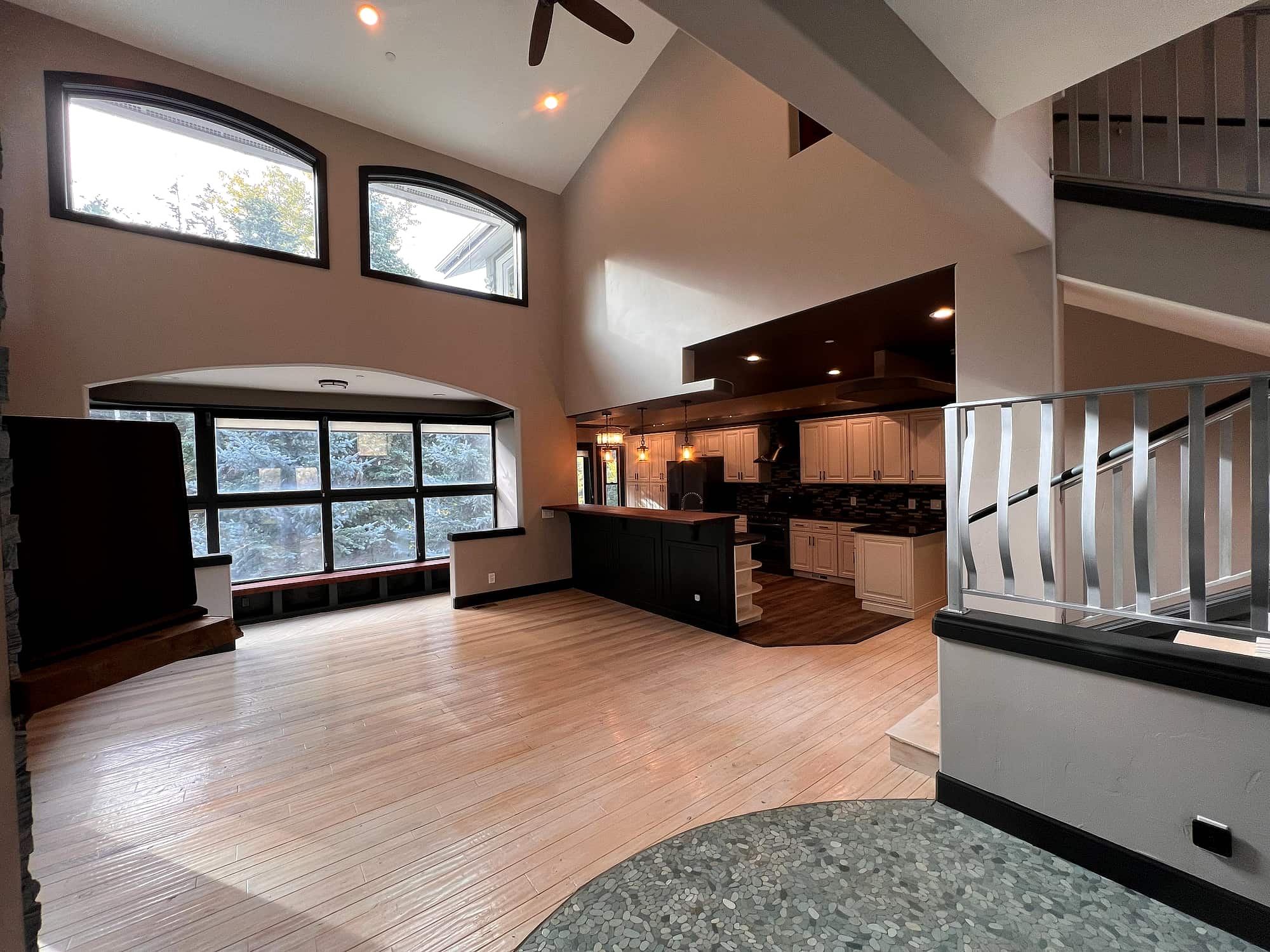 The vaulted great room, arched windows framing the trees
