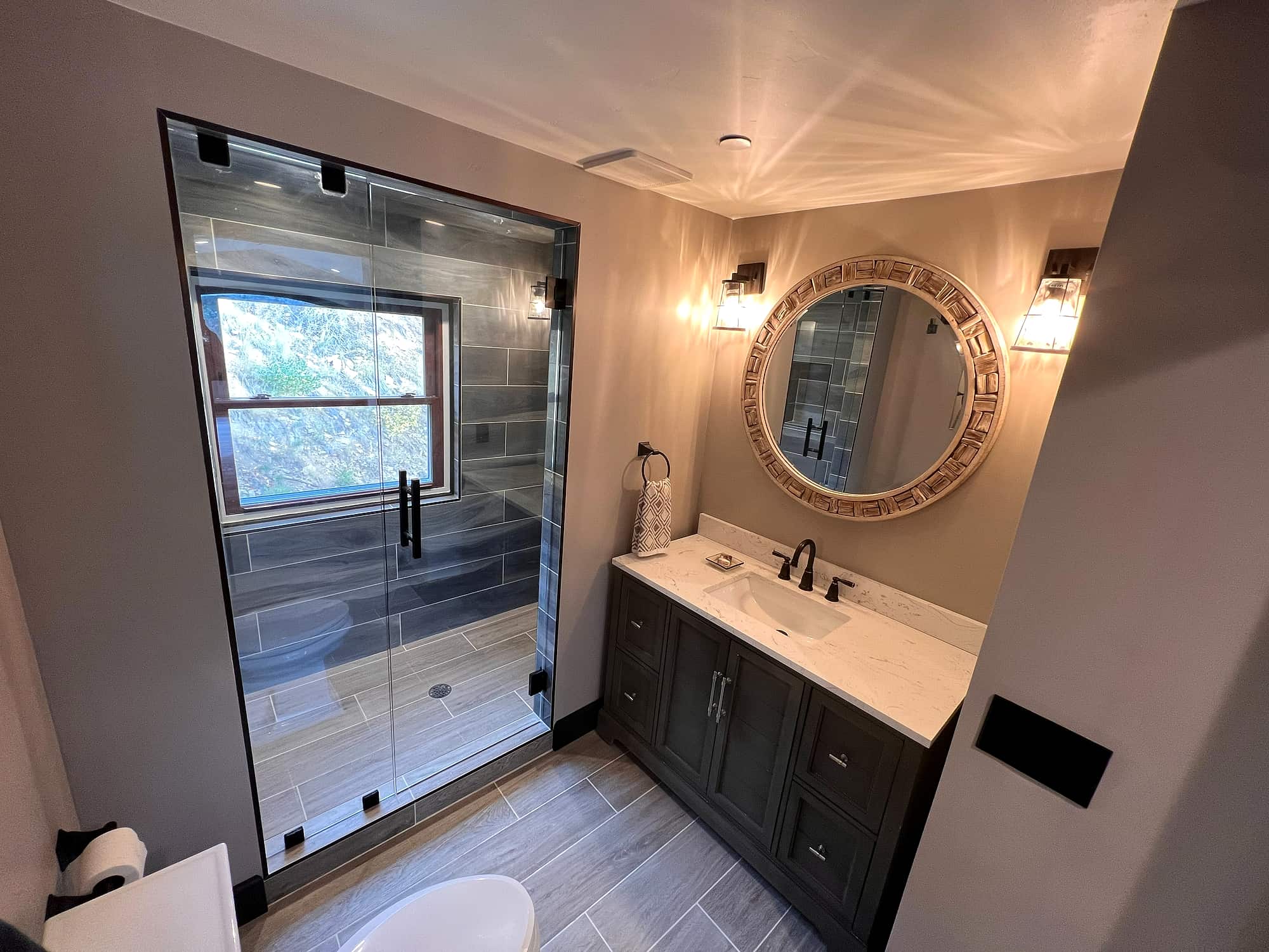 The primary bath, with a glass shower and round mirror over the vanity