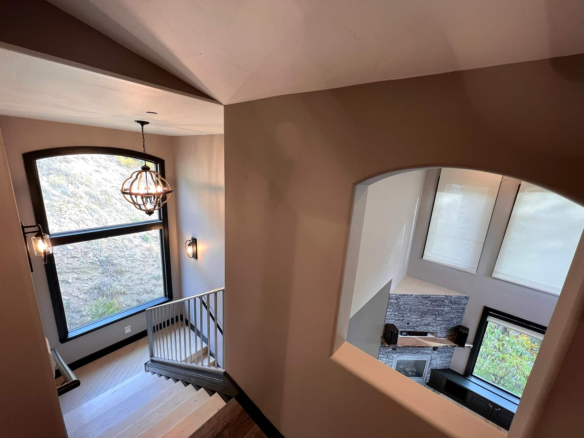 The stairwell, arched window above a cut-out view to the great room
